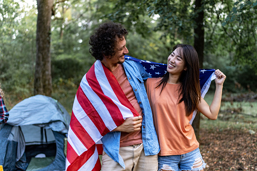 Young smiling couple holding American flag on back outdoors