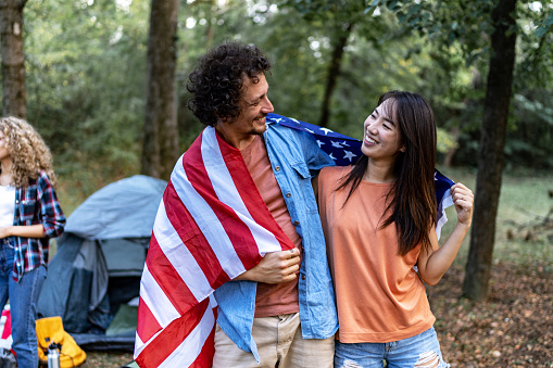 Young smiling couple holding American flag on back outdoors