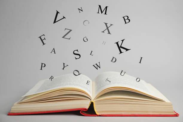 istock Open book with letters flying out of it on light background 1878153557