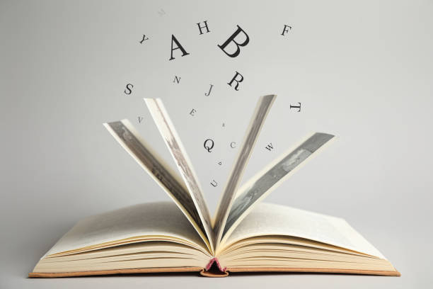 istock Open book with letters flying out of it on light background 1878156635