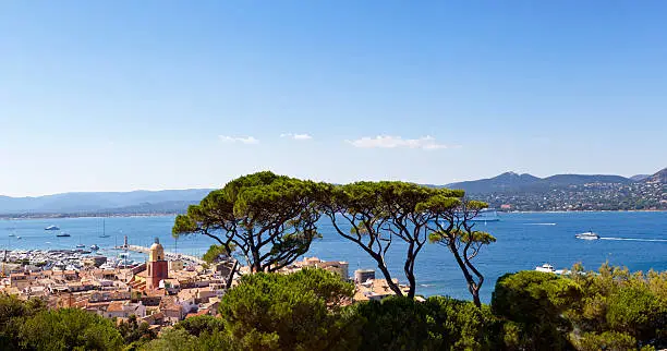 Across the Gulf of St Tropez, with the town St Tropez in the foreground and the iconic church tower of Notre Dame of the Assumption. In the bay is moored a cruise ship and across the the Gulf from the town lies the1960’s holiday village creation, Port Grimaud and on the hilltop peak behind, the perched 11th century village of Grimaud with it’s castle.Good copy space