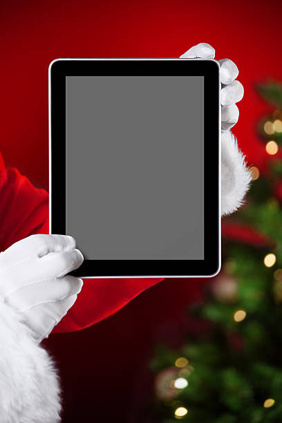 Santa holding a tablet with blank space stock photo