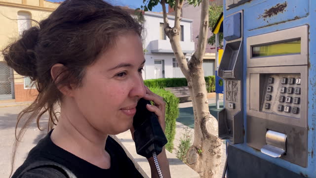 Woman using old public pay phone in the street