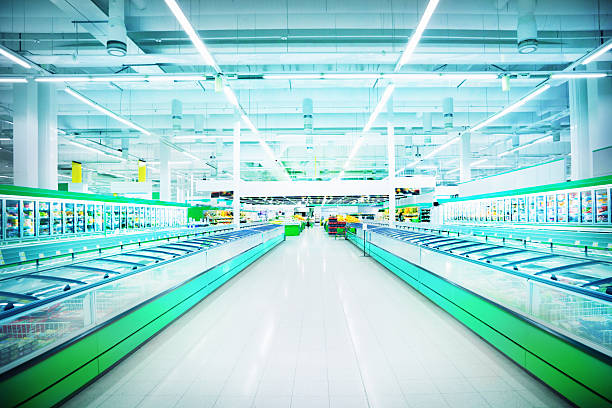 Empty, brightly-lit aisle in large supermarket Various products in a supermarket refrigerated section supermarket photos stock pictures, royalty-free photos & images