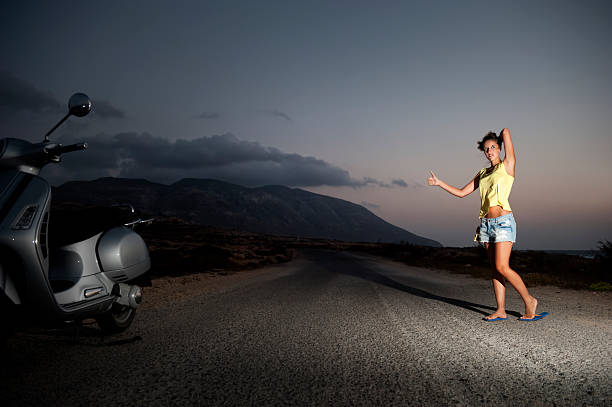 Young female hitchhiking alone in the countryside stock photo