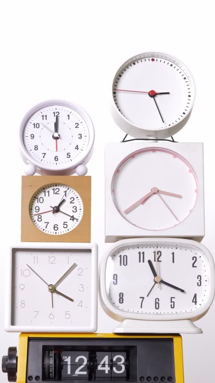 Many clocks turning to tell the time on a white background.