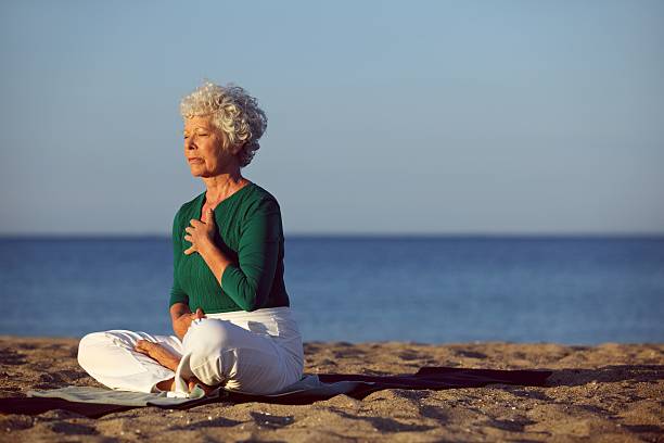 istock Senior woman in meditation by ocean 187835737