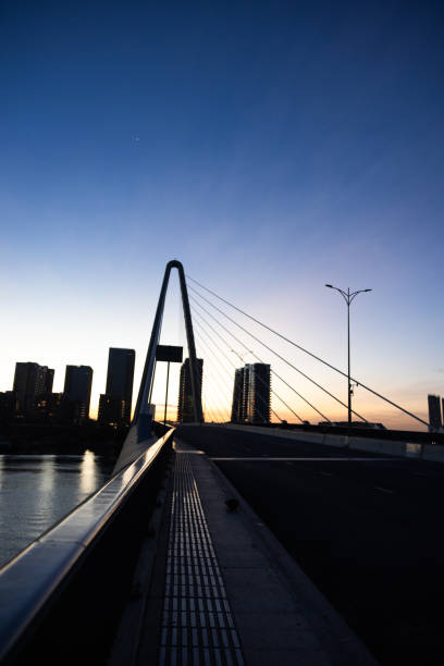 horizonte de la ciudad con puente colgante y reflejo del agua al anochecer - photography suspension bridge water night fotografías e imágenes de stock