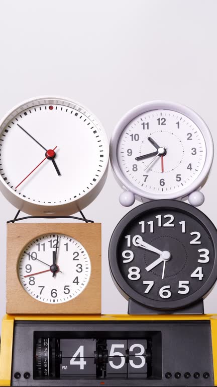 Many clocks turning to tell the time on a white background.