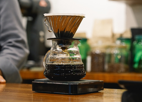 Grinding coffee beans in a manual coffee grinder on a wooden table. Copy space