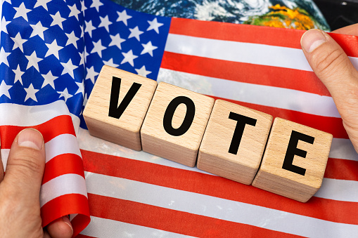American flag held in hands, US elections, text vote on wooden blocks, United States election concept