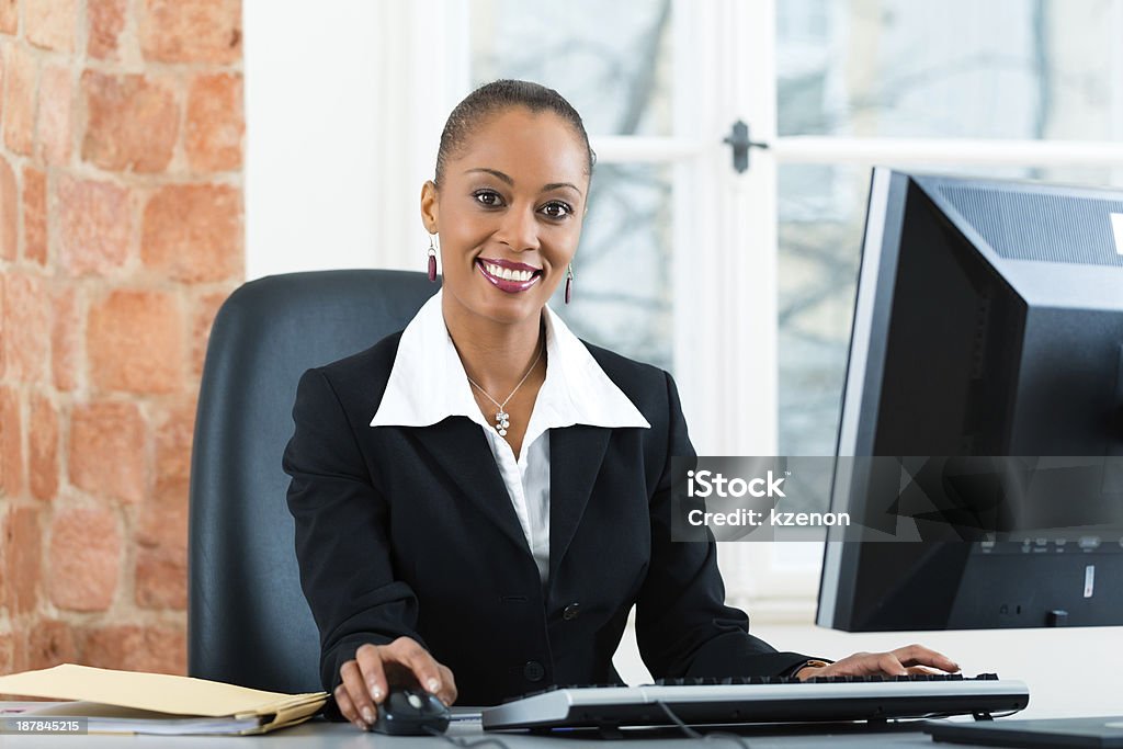 Businesswoman sitting at desk working on computer Young female lawyer or secretary working in her office on a Computer or Pc File Clerk Stock Photo