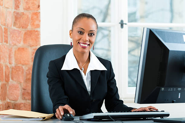 Businesswoman sitting at desk working on computer Young female lawyer or secretary working in her office on a Computer or Pc file clerk stock pictures, royalty-free photos & images