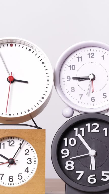 Many clocks turning to tell the time on a white background.