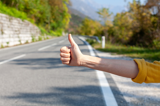 Woman Hand Hitchhiking on a Road in Early Autumn