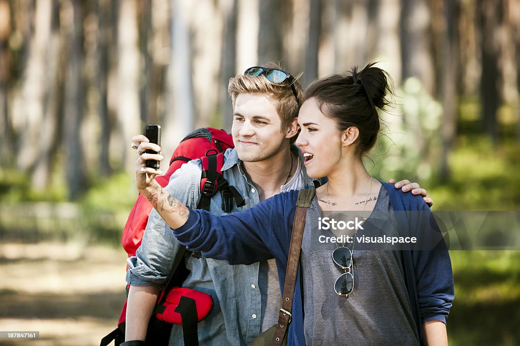 Couple taking a photograph of themself Trendy couple hiking in the woods., taking pictures of themself. 20-29 Years Stock Photo
