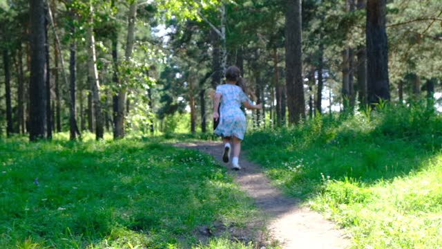 Child girl in the meadow, forest, walking, running  and having fun time at the sunny summer day, breathing. Forest after rain with fresh air. Enjoying Life