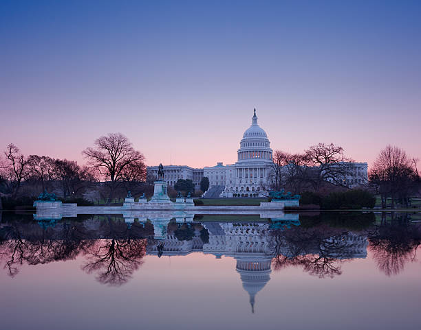 Sunrise behind the dome of Capitol in DC Brightly lit dawn sky behind the illuminated dome of the Capitol in Washington DC with the pool and statues capitol building washington dc stock pictures, royalty-free photos & images