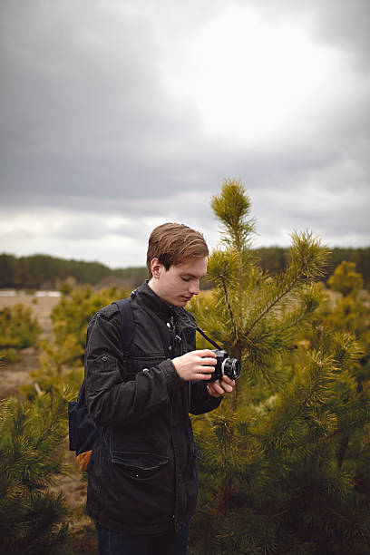 istock Young adult with photo camera in pine trees 187849694