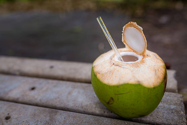 Freshly opened coconut drink with straw Coconut with straw on the floor drinks utensil stock pictures, royalty-free photos & images