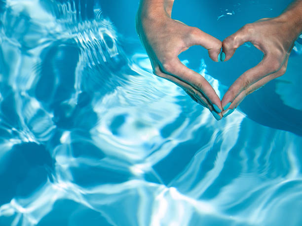 cuore con le mani in acqua turchese - camminare nellacqua foto e immagini stock