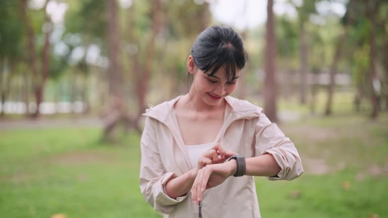 An Asian woman in workout attire is exercising with the smartwatch's fitness function in a public park. Capture the blend of technology and outdoor fitness for a vibrant image.