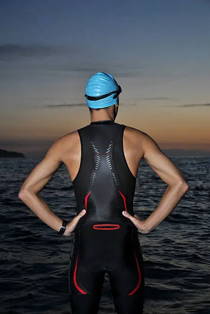 young athlete triathlon in front of a sunrise over the sea