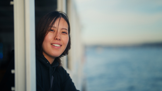 An Asian female tourist is traveling alone on a ferry.