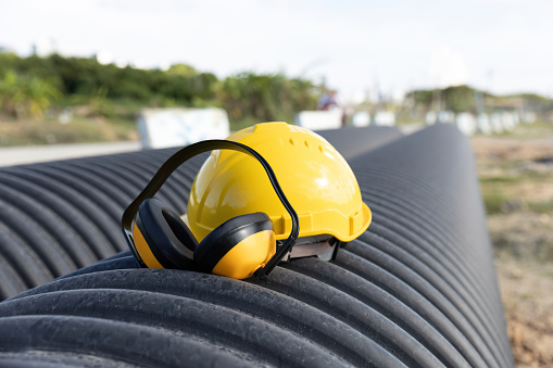 industrial work safety equipment. Construction Noise. Heavy Machinery Reduction. Yellow protective ear muffs hang on machines in constuction site.  The concept is a PPE device