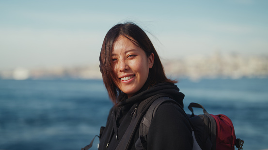 An Asian female tourist is traveling alone on a ferry.