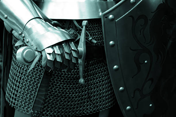A knight in steel armor posing with his sword and shield stock photo