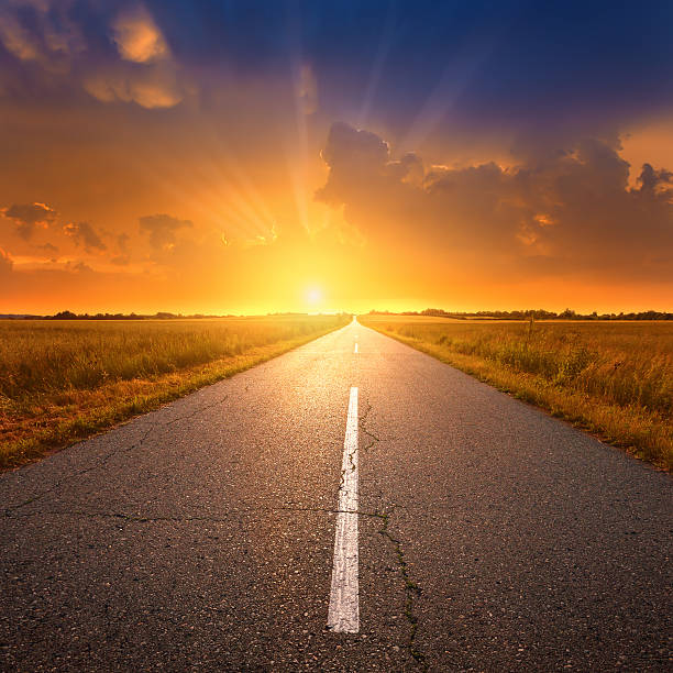 istock Driving on an empty asphalt road towards a setting sun 187878194