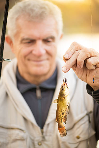 Fisherman Senior Fisherman holding fish on the hook. bullhead fish stock pictures, royalty-free photos & images