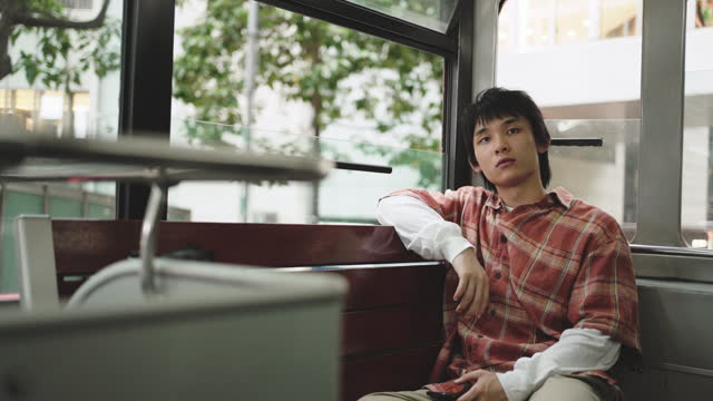 Asian Chinese young man looking away sitting in double-decker bus in Hong Kong Island alone