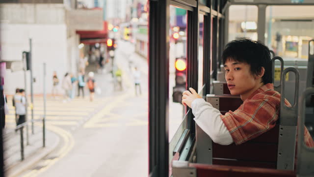 Asian Chinese young man singing sitting in double-decker bus in Hong Kong Island alone