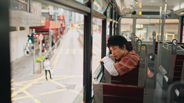 Asian Chinese young man singing sitting in double-decker bus in Hong Kong Island alone