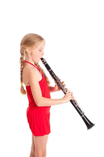 young girl in red playing clarinet against white background
