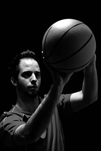 black & white low-key studio shot of basketball-player throwing ball