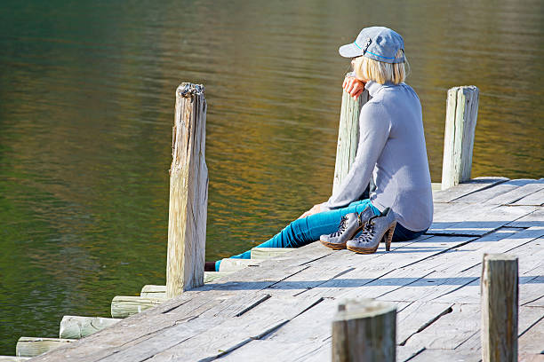istock Woman sitting on dock with shoes 187884600