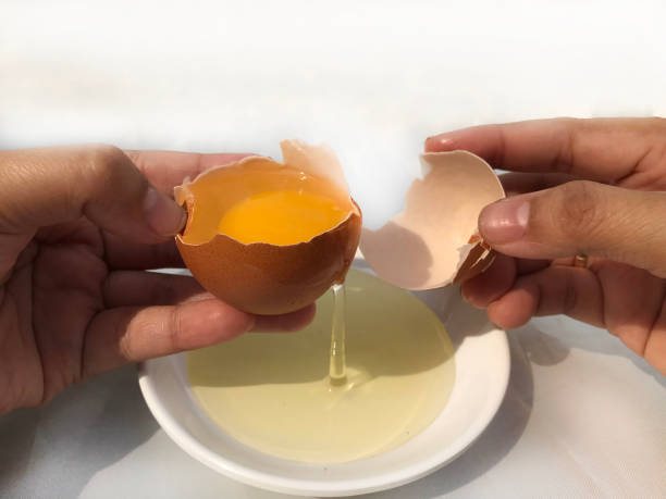 istock A woman's hand cracks an egg to separate the egg white and yolk 1878870484
