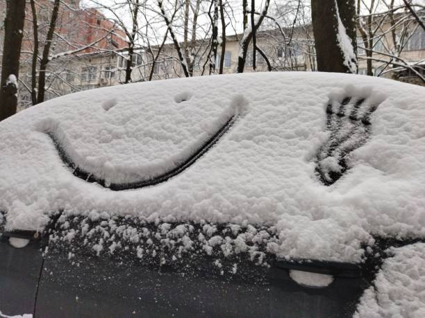 istock Face with a smile is painted on a car covered with snow in winter. 1878933638