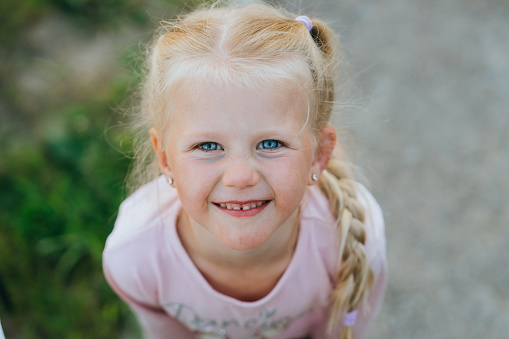 Directly above view portrait of a cute blonde preschooler child lying on the grass