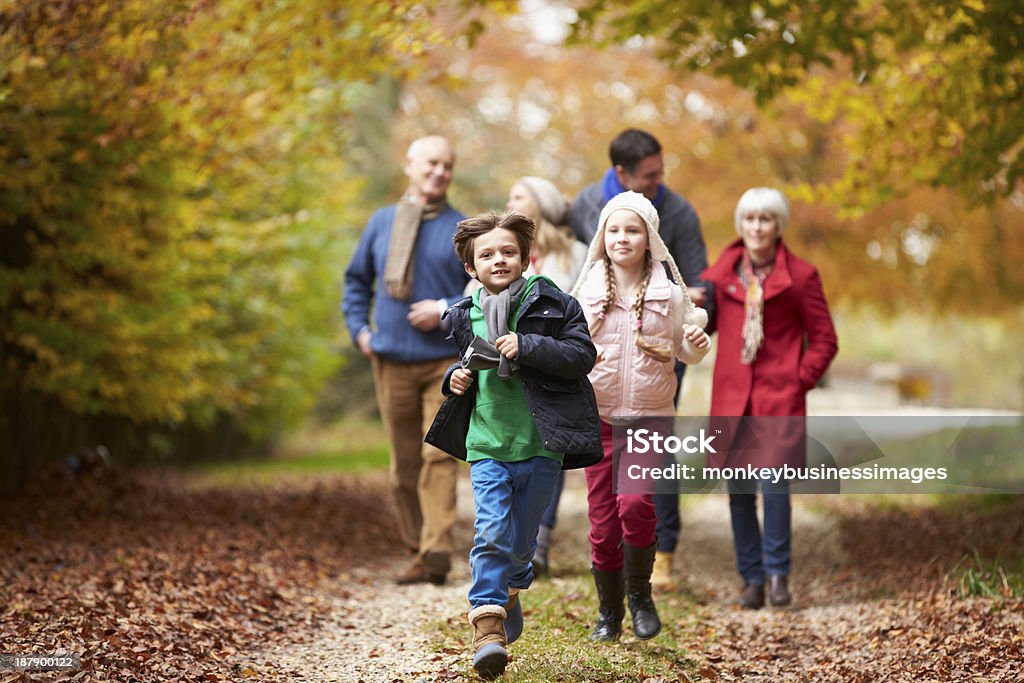 Multiple generations of a family walking in fall Multl Generation Family Walking Along Autumn Path Children Running And Playing In Front Outdoor Family Caption Autumn Stock Photo