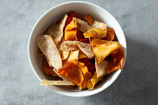 A top down view of a bowl of vegetable root chips.