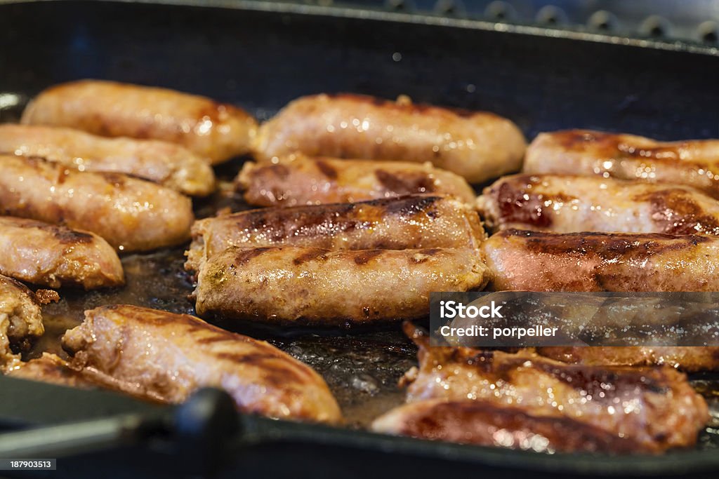 Fried Sausage Cooking a succulent and spiced sausage on a grilling pan Barbecue - Meal Stock Photo