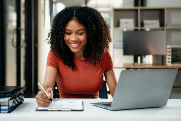 istock Young woman typing on tablet and laptop while sitting at the working in office 1879074091
