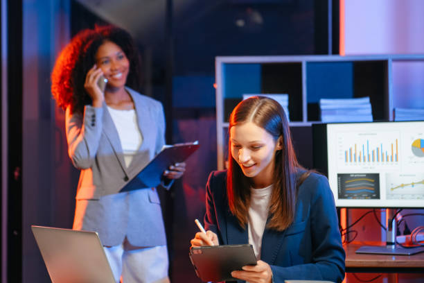 istock Two business workers talking on the smartphone and using laptop at the office. overtime 1879074735