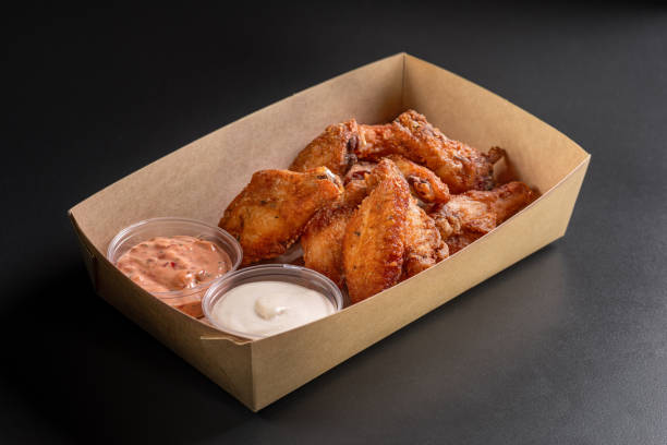 istock Fried chicken wings in a paper box on a dark background. Snacks in a paper box 1879112212