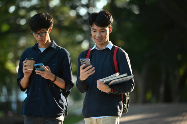 istock Two Asian college student friends using a smartphone while walking in the campus 1879125161