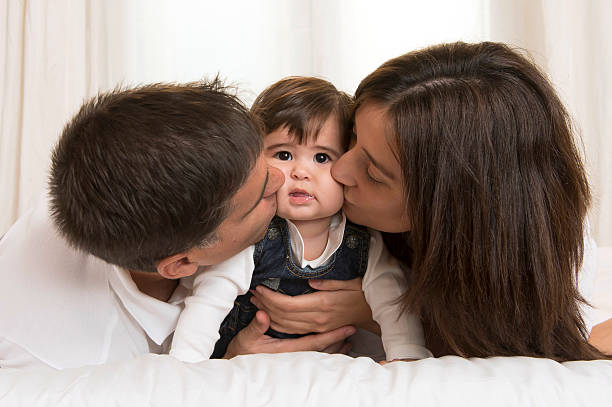 istock Mother and Father Kissing Daughter 187913200